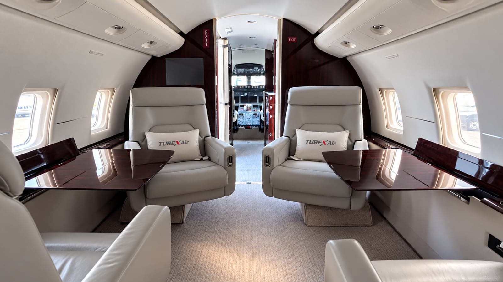 Challenger 604 kabininin kokpite doğru genel görünümü: karşılıklı deri koltuklar ve ceviz kaplama masalar